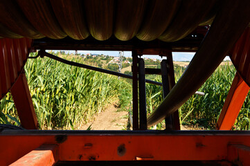 Fototapeta na wymiar Agricultural irrigation system with a big hose reel in a cornfield during summer.