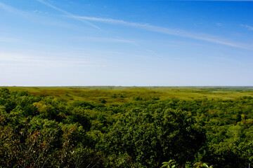 A green field and valley in the Flint Hills of Kansas with blue sky