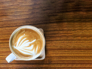 a cup of latte coffee with foam on the brown wooden background top view