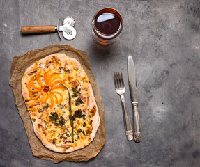 Decorated Traditional Alsatian Pie, Tart Flambe or Flammkuchen with Silverware and Glass of Red Wine on Shabby Chic Vintage Wooden Grey Background. Retro Styled Food Background.