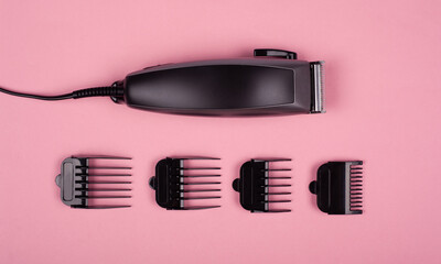 barber clipper for haircuts with nozzles of different sizes on a pink background top view