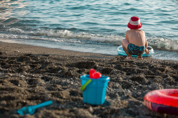 Toddler is playing on the beach sea, back view in the evening. Summer holyday.