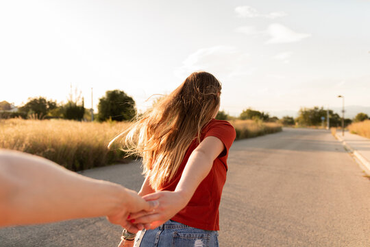 Adolescente rubia patinando por la carretera junto a su pareja dados de la mano durante el proceso de desescalada en Espa&ntilde;a al atardecer