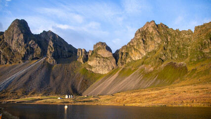 Beautiful Iceland landscapes with small houses in front of vast mountains.