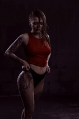 a gorgeous young woman in a wet red top and black panties poses sexily in a dimly lit Studio. Girl...