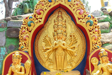 Fototapeta premium View of carved golden statue of eleven-headed Avalokiteśvara bodhisattva who embodies the compassion of all Buddhas. Monument is located in Buddha Garden in Kathmandu city, Nepal.