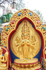 View of carved golden statue of eleven-headed Avalokiteśvara bodhisattva who embodies the compassion of all Buddhas. Monument is located in Buddha Garden in Kathmandu city, Nepal.