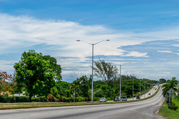 Vehicles driving along the Elegant Corridor highway in Montego Bay, Jamaica. Cars drive on the left hand side of the road.