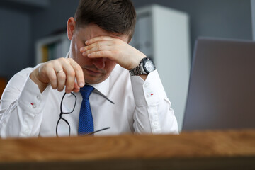 Tired male office worker sitting at table resting