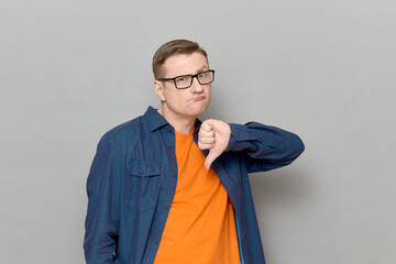 Portrait of funny man giving thumb down sign of disapproval