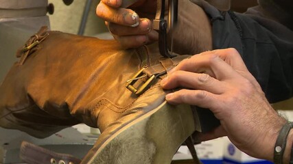 close up of a man using an industrial sewing machine to repair a woman's boot