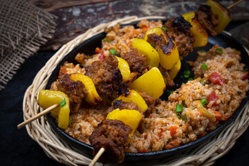 Seitan and bell pepper kebabs with rice pilaf served in cast iron dish