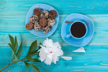 A portion of homemade energy balls and a Cup of black coffee on a blue wooden table. Delicious, healthy dessert. Breakfast. Lifestyle. The view from the top. White flower