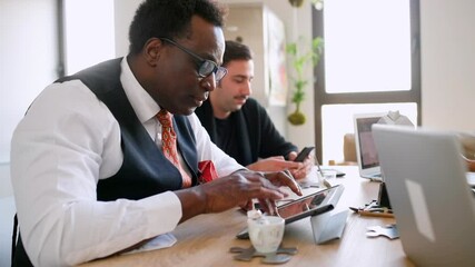 MS Men sitting at table and using tablet and smart phone / Milan, Italy