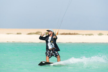 kiter does a difficult trick on a background of transparent water and blue sky