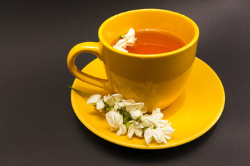 Yellow cup of herbal acacia tea, front view