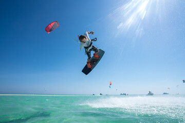 kiter does a difficult trick on a background of transparent water and blue sky