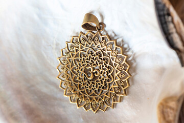 Brass pendant with om symbol in lotus round shape mandala on white shell background - obrazy, fototapety, plakaty
