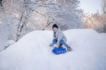 Winter fun in the city. A boy rides on a slide of ice.