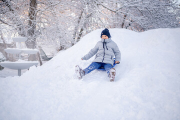 Fototapeta na wymiar Winter fun in the city. A boy rides on a slide of ice.