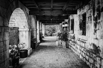 Exterior corridor on ground floor porch of vintage mansion/ great house in the Caribbean. Brick walls and flooring with columns and arch design.