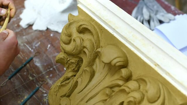 Sculptor create clay model of a Corinthian capitel with scrolls and unfurled acanthus leaves in restoration workshop