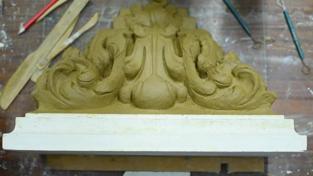 Sculptor create clay model of a Corinthian capitel with scrolls and unfurled acanthus leaves in restoration workshop