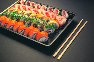 Japanese sushi rolls in the shape of a line on black background top view