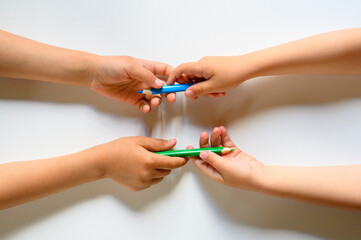 kid's hands share each other colored pencils on a white background