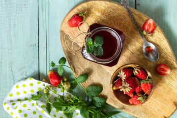 Homemade preservation concept. Strawberry berry syrup and fresh strawberry berries on a wooden table. Top view flat lay background. Copy space.