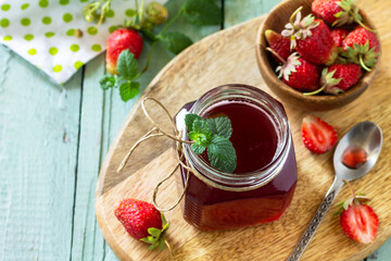 Homemade preservation concept. Strawberry berry syrup and fresh strawberry berries on a wooden table. Copy space.