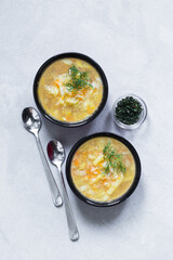 Vegan vegetable soup of cabbage, potatoes, carrots with dill on a bowl on a light gray background top view