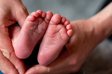 Beide Hände der Mutter halten beide Füsse eines Neugeborenen Kindes, Säuglings, Baby in Herzform...