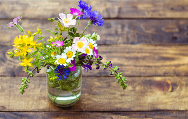 
field flowers of many colors on wooden background