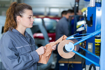young female mechanic taking roll sheets to wipe her hands