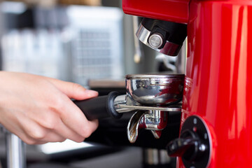 Close up shot of professional bartender preparing espresso coffee in exclusive cafe bar or cafeteria. He using coffee mill or grinder.