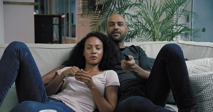 MS Couple reclining on sofa in living room and watching TV / Claremont, Cape Town, South Africa
