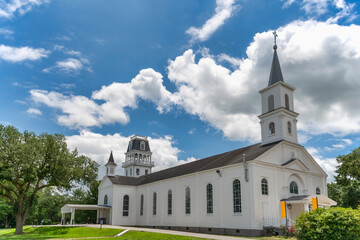 Fototapeta na wymiar St. Charles Borromeo Catholic Church in Grand Coteau Louisiana Under Blue Cloudy Sky