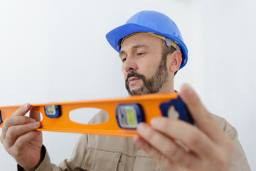 portrait of builder man in uniform standing with spirit level