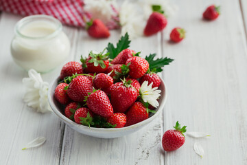 Bowl of red juicy strawberries on white wooden table. Healthy and diet snack food concept.