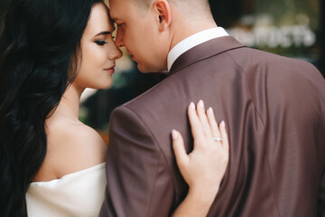 Bride and groom. Close up portrait of a man in a suit and brunette woman in a white wedding dress. In the city against the backdrop of a shop window, on the wedding day. European appearance. 