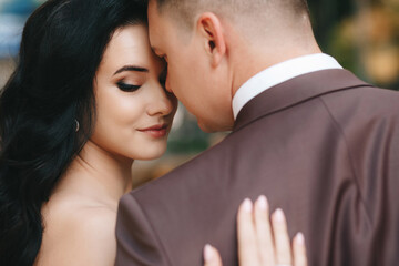 Bride and groom. Close up portrait of a man in a suit and brunette woman in a white wedding dress. In the city against the backdrop of a shop window, on the wedding day. European appearance. 