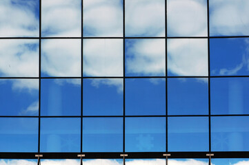 Reflections of blue sky and white clouds in windows.