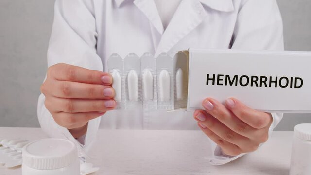 Proctologist with pack of hemorrhoidal suppositories, closeup