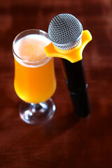 Microphone and a glass of beer on a dark background in the interior. The concept of a karaoke...