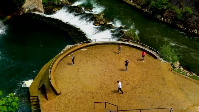 Aerial view over tourists during their visit to big waterfall of river Pliva in city of Jajce, Bosnia and Herzegovina.