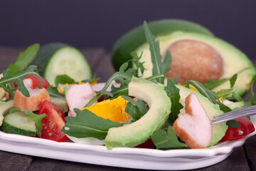 Avocado salad with rucola, eggs and chicken  on rustic wooden table. Healthy food concept.