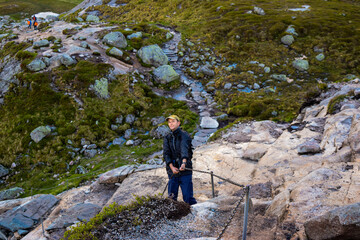 Chains on the way to famous Kjeragbolten help tourists climb steep cliffs. Norway.