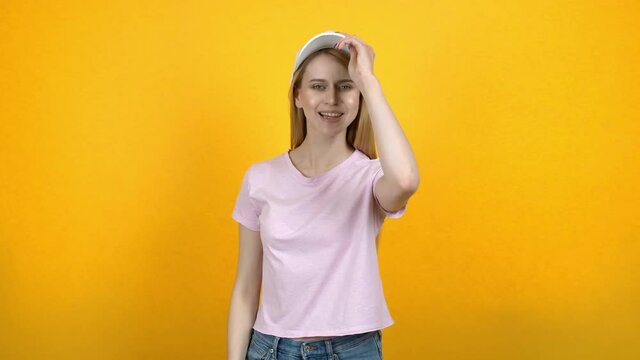 Young woman trying on different caps against color background