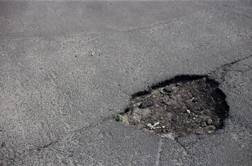 Broken asphalt and cracks on the road surface